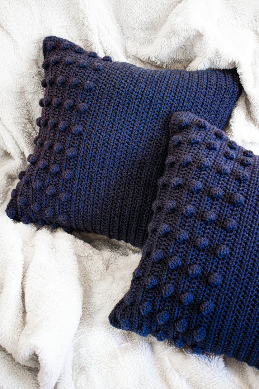 Two blue textured pillows on a white fluffy surface