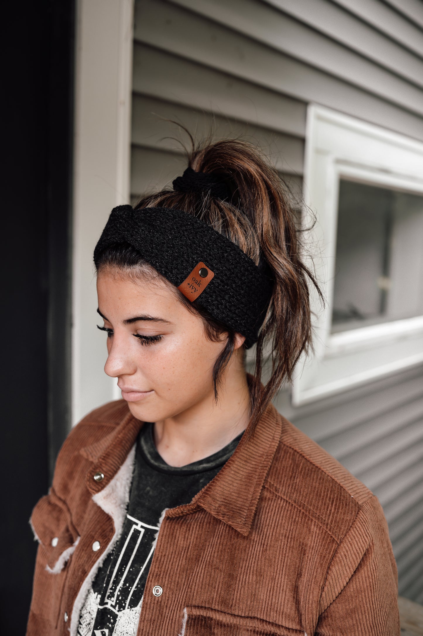 A girl wearing a dark grey heather knit headband with visible brand tag.