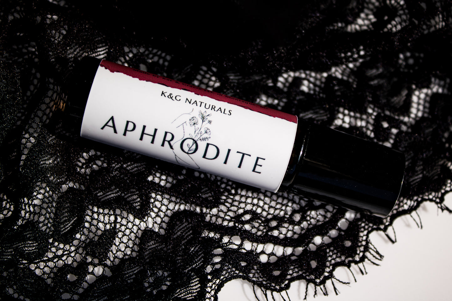 Roll-on bottle labeled 'Aphrodite' by K&G Naturals on black lace fabric