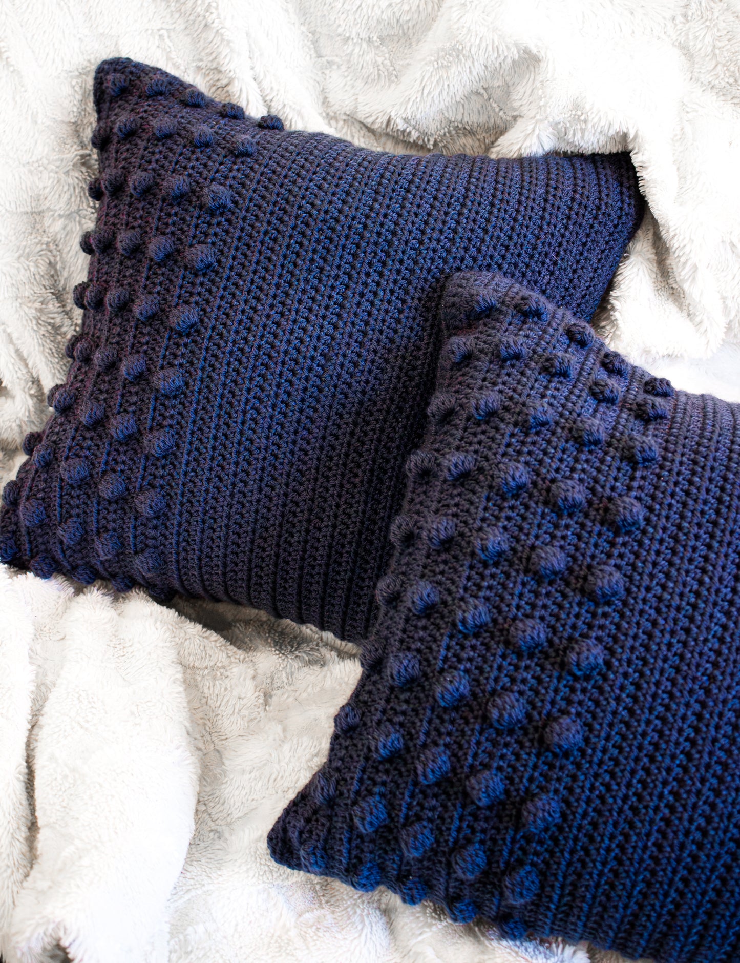 Two blue textured pillows on a white fluffy surface