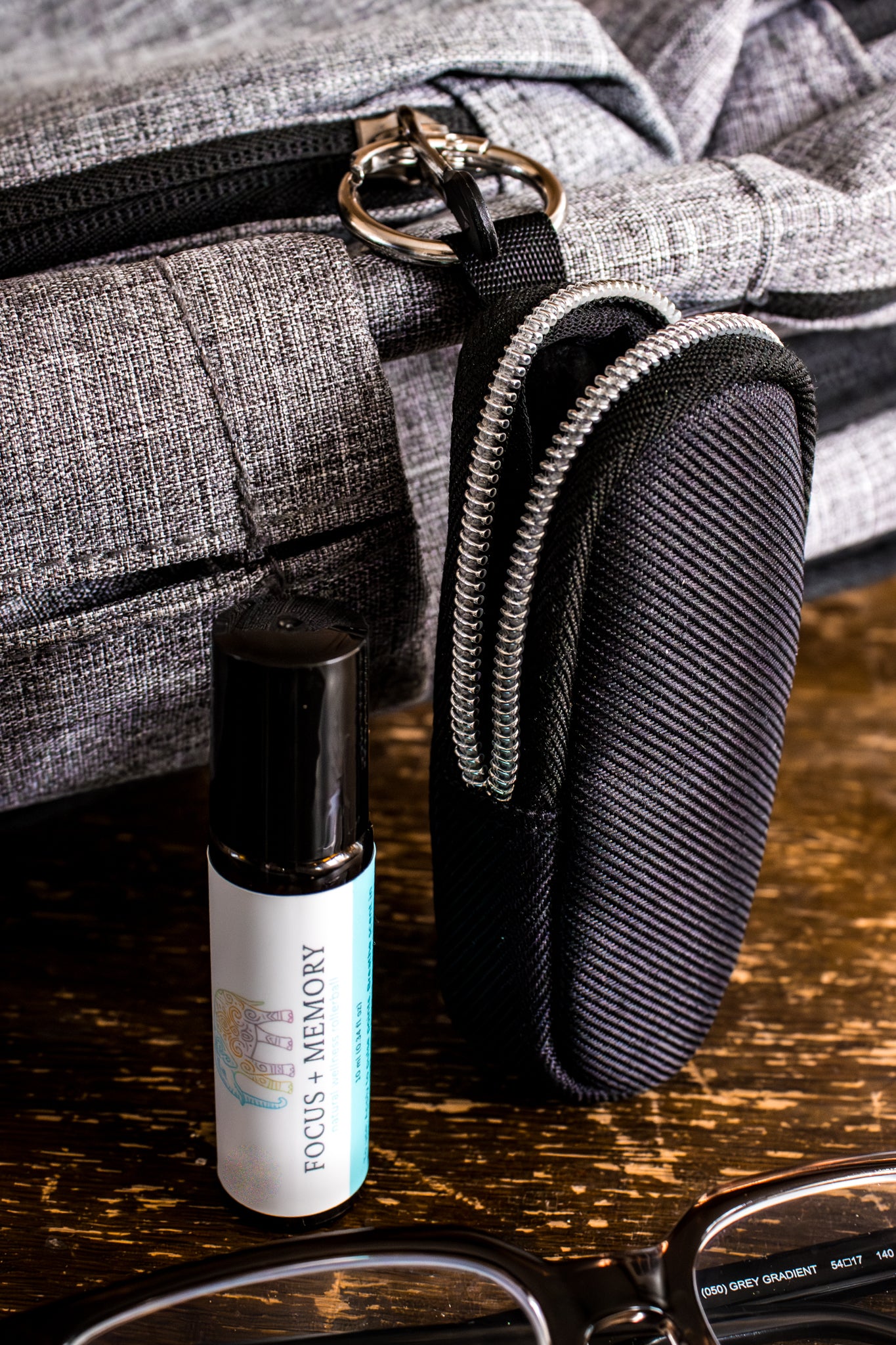 Roll-on bottle labeled 'Focus of Memory' with a black pouch attached to a backpack