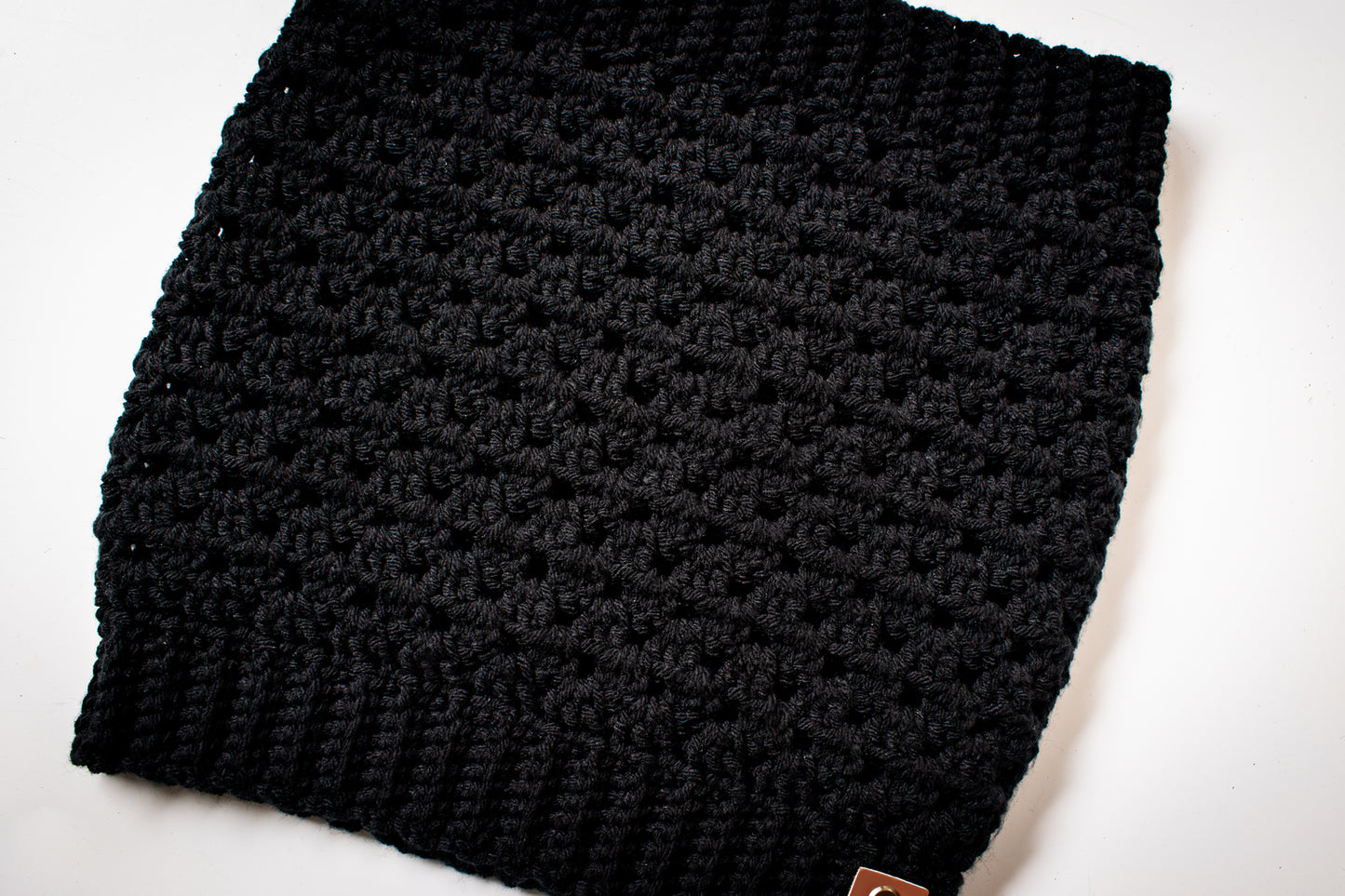 Black crocheted cowl on a white surface