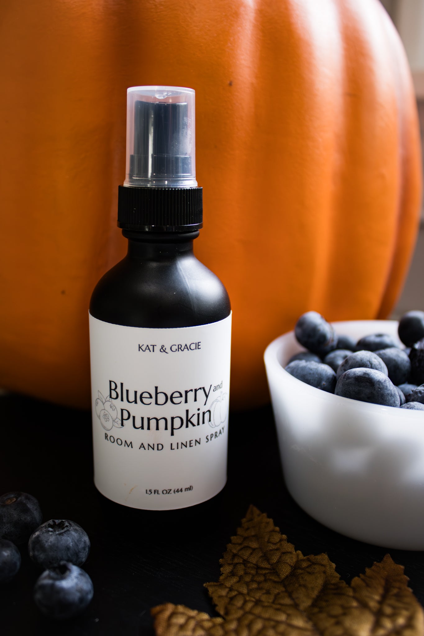 Bottle of 'Blueberry & Pumpkin' room and linen spray with a pumpkin and blueberries in the background.
