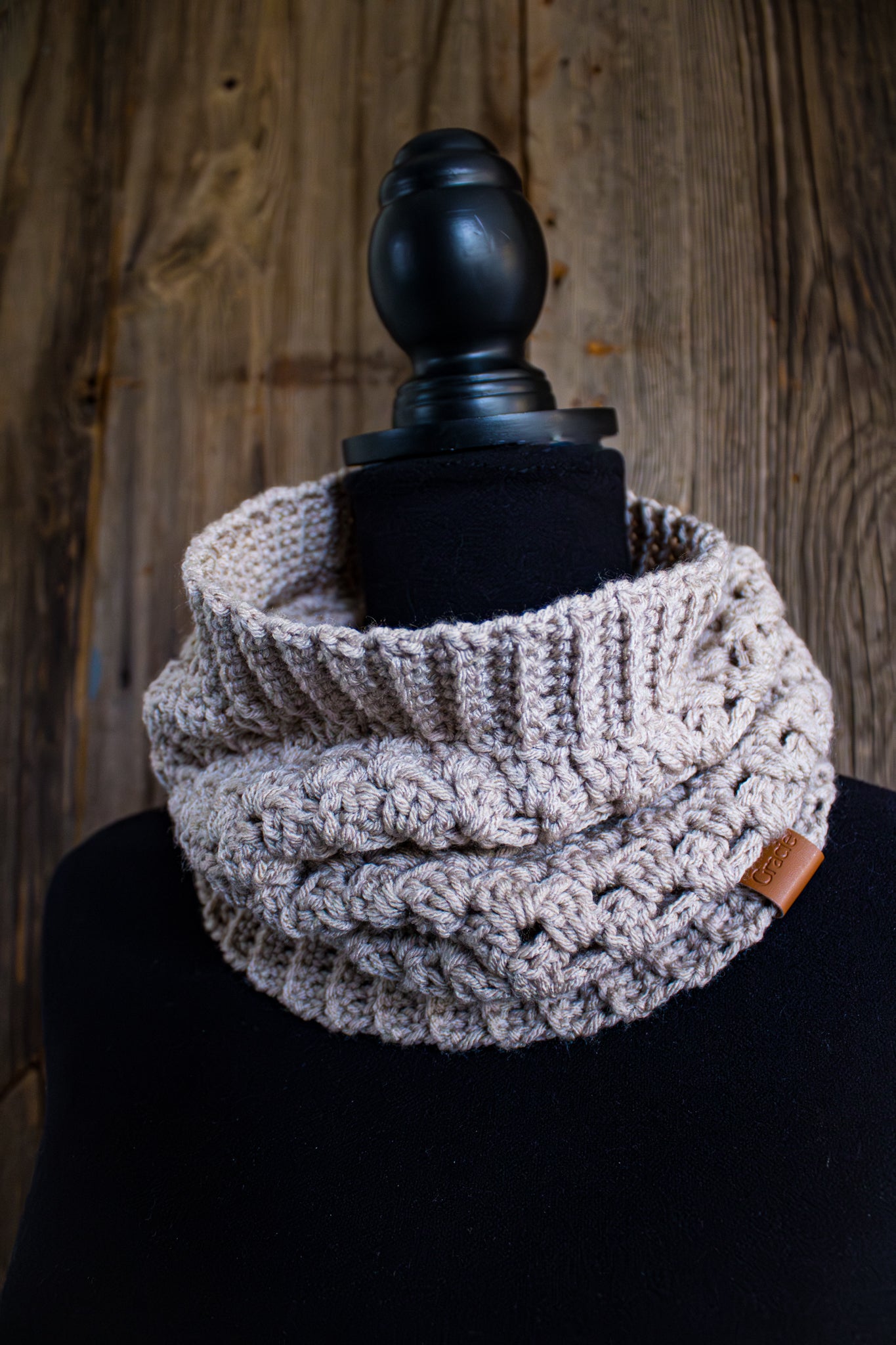 Crocheted cowl on a mannequin against a wooden background