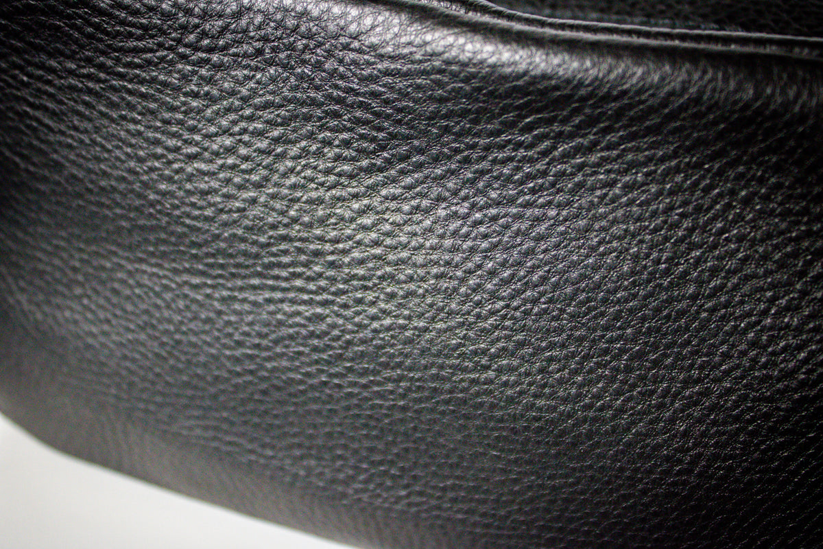 A close-up up a black pebbled leather Dopp bag.