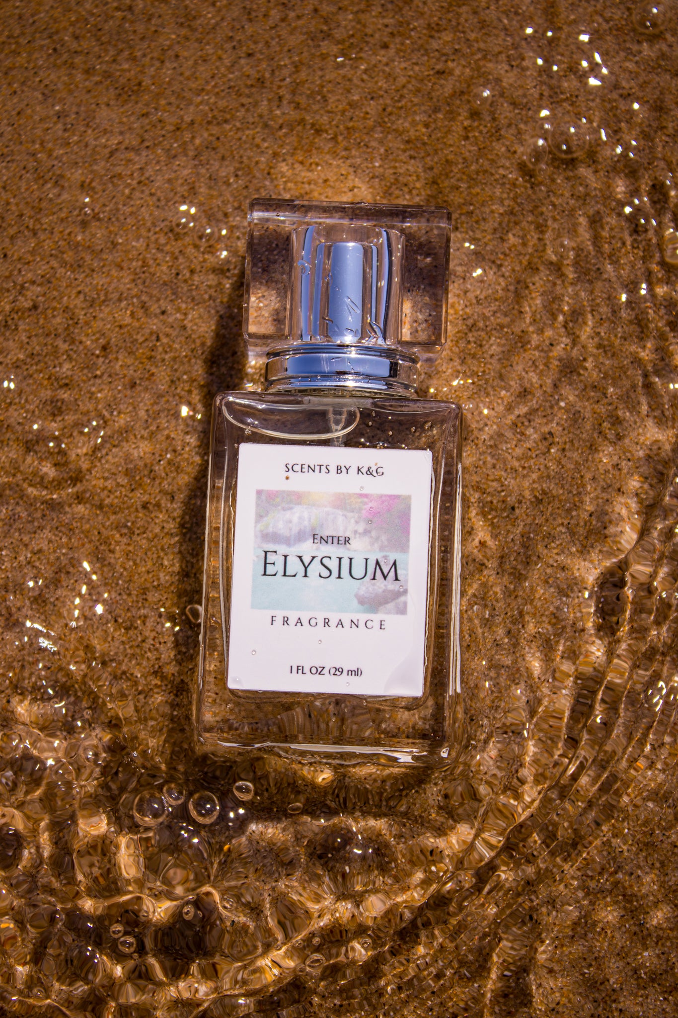 Perfume bottle labeled 'Elysium' on wet sand