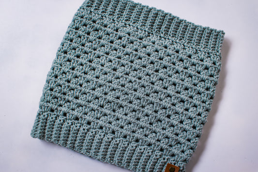 Blue-green colored crocheted cowl on a white background