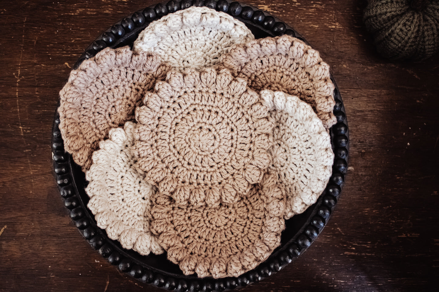 Crocheted off-white and khaki coasters in a centerpiece bowl.
