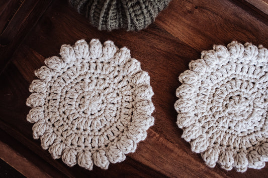 Two crocheted coasters on a wooden surface