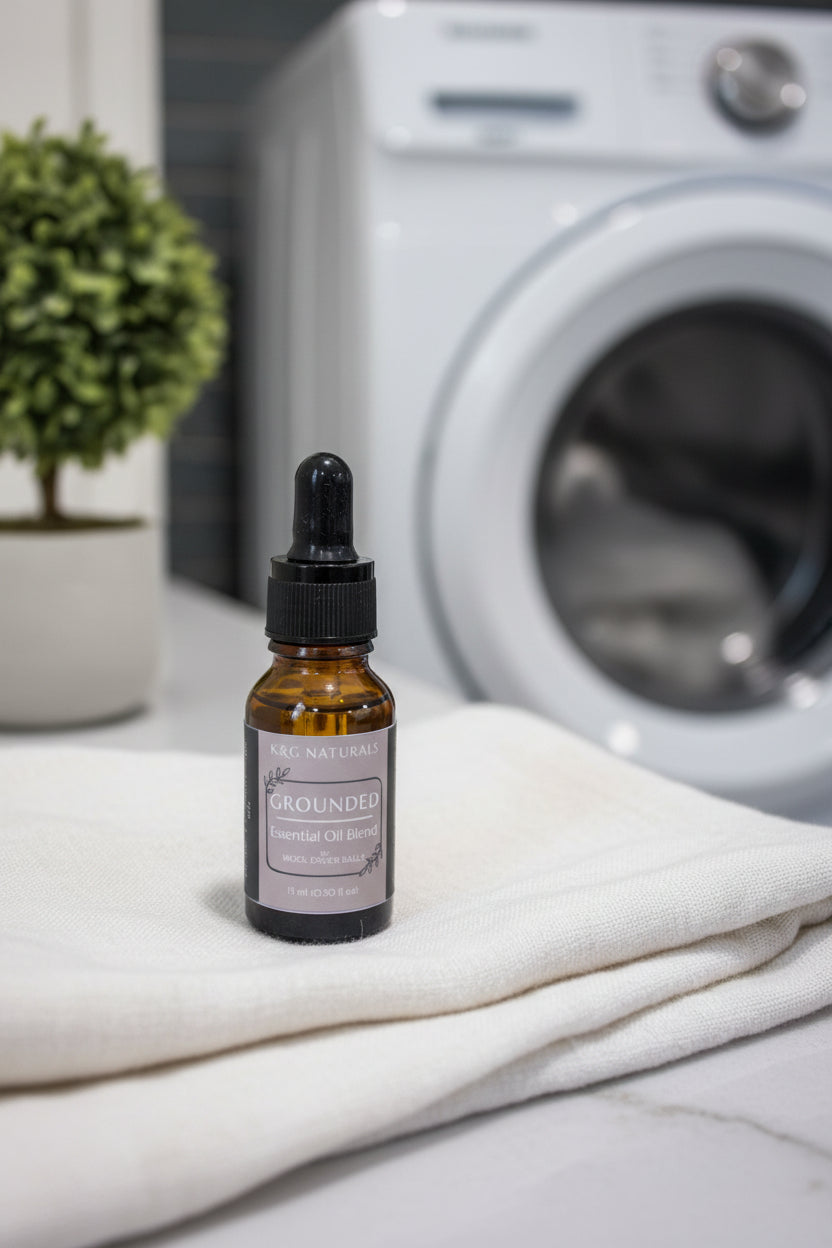 A bottle of 'Grounded' essential oil blend dryer ball drops in a neutral laundry room
