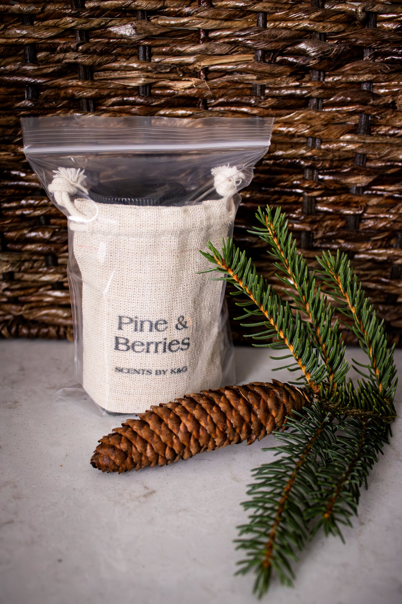 Scented product labeled 'Pine & Berries' with a pine cone and branch on a textured background