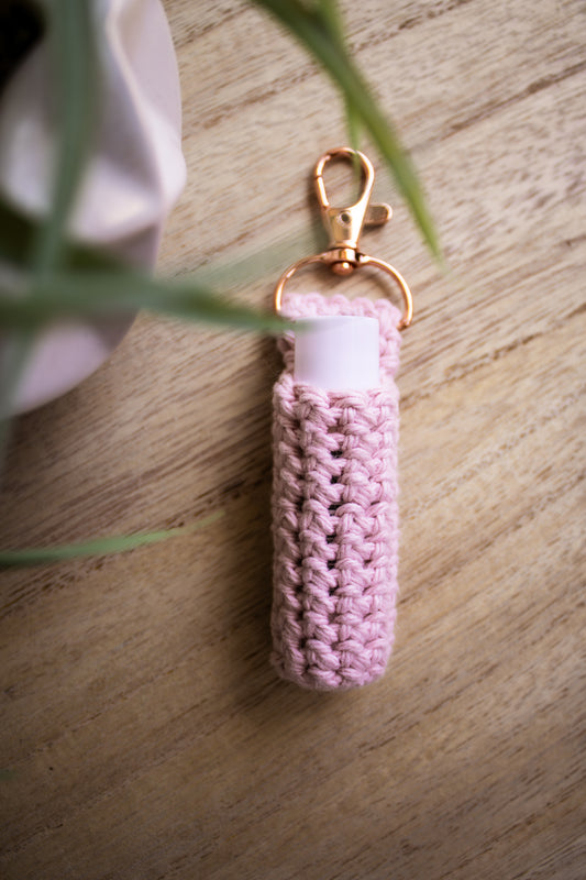 Rose colored chapstick holder keychain with a rose gold clasp on a wooden surface