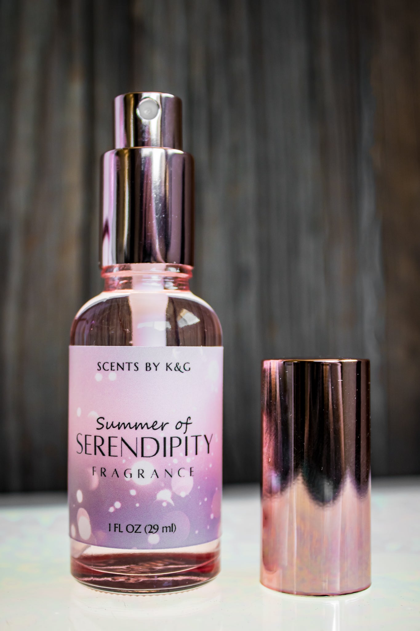Rose gold bottle and cap of 'Scents by K&G' Summer of Serendipity fragrance on a neutral background