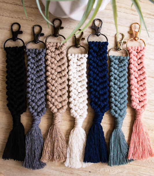 Set of braided keychains in various colors on a wooden surface.