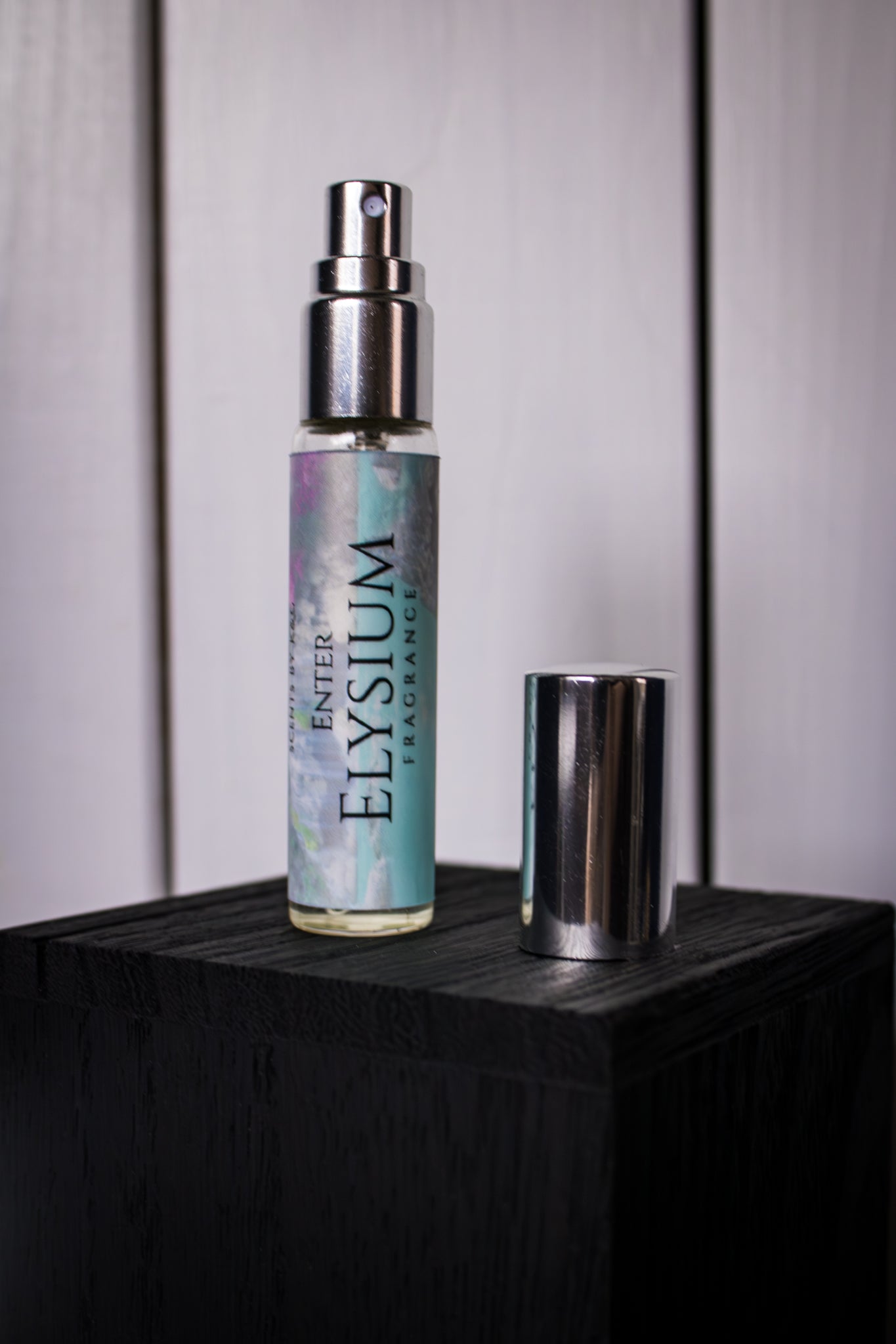 Enter Elysium perfume bottle on a dark surface with a neutral background