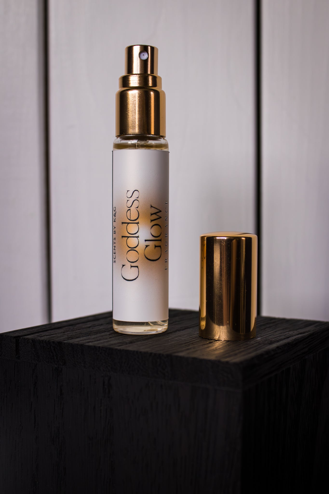 Perfume bottle labeled 'Goddess Glow' on a wooden surface with a neutral background