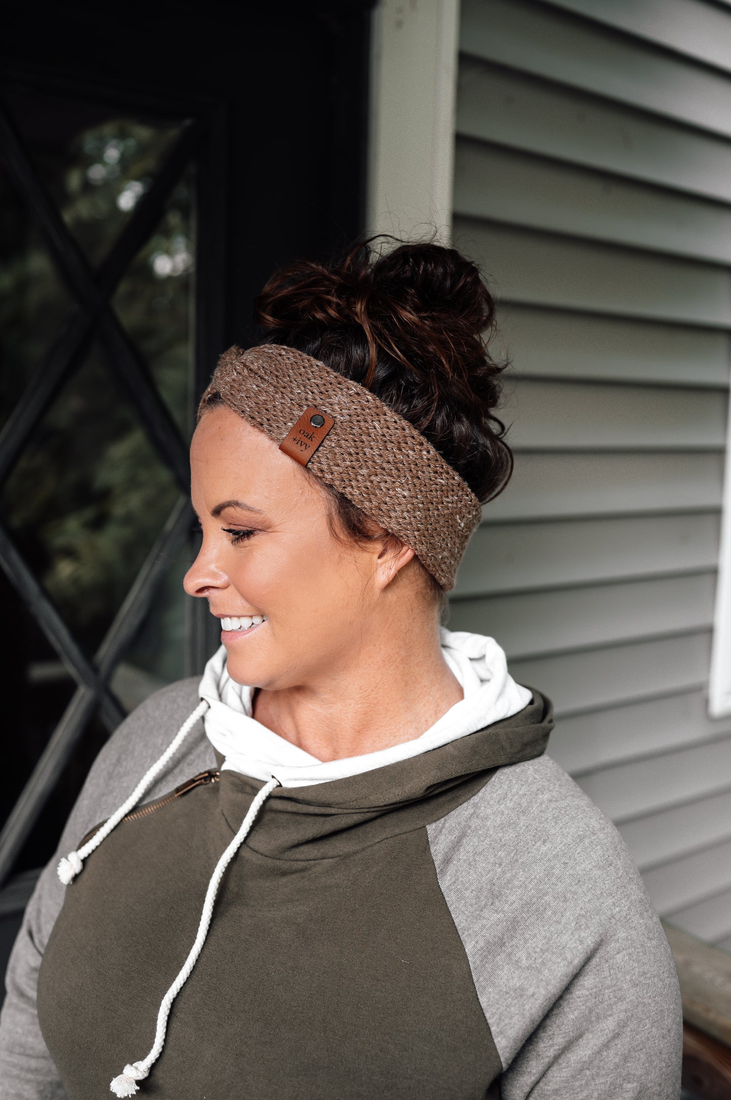 A woman wearing a brown tweed knit headband with visible brand tag.