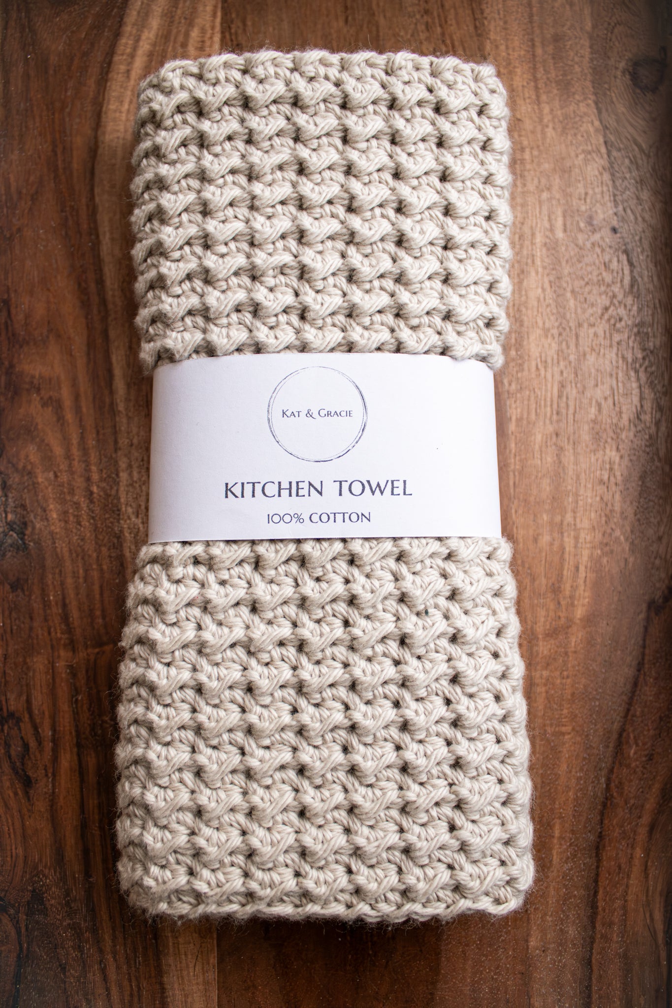 Beige kitchen towel with a label on a wooden surface
