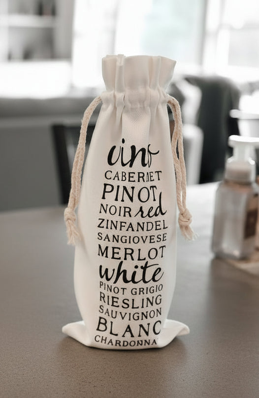A canvas wine bag with a list of wine types on a concrete counter with a living room in the background