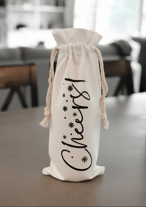 A canvas wine bag reading 'CHEERS' on a concrete counter with a living room in the background.